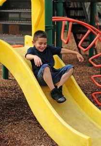 Young boy on slide - 'r kids family center encourages children to become community-minded citizens