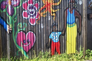 Fence artwork depicting family, hearts and flowers in beautiful hues.