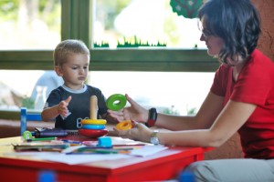 Child learning with an adult: ‘r kids Family Center offers a number of educational services to support children and their families.